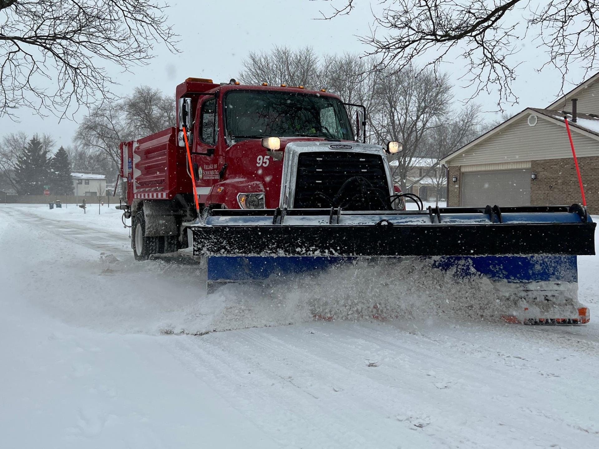 A Village of Schaumburg snow plow clears snow from a road.